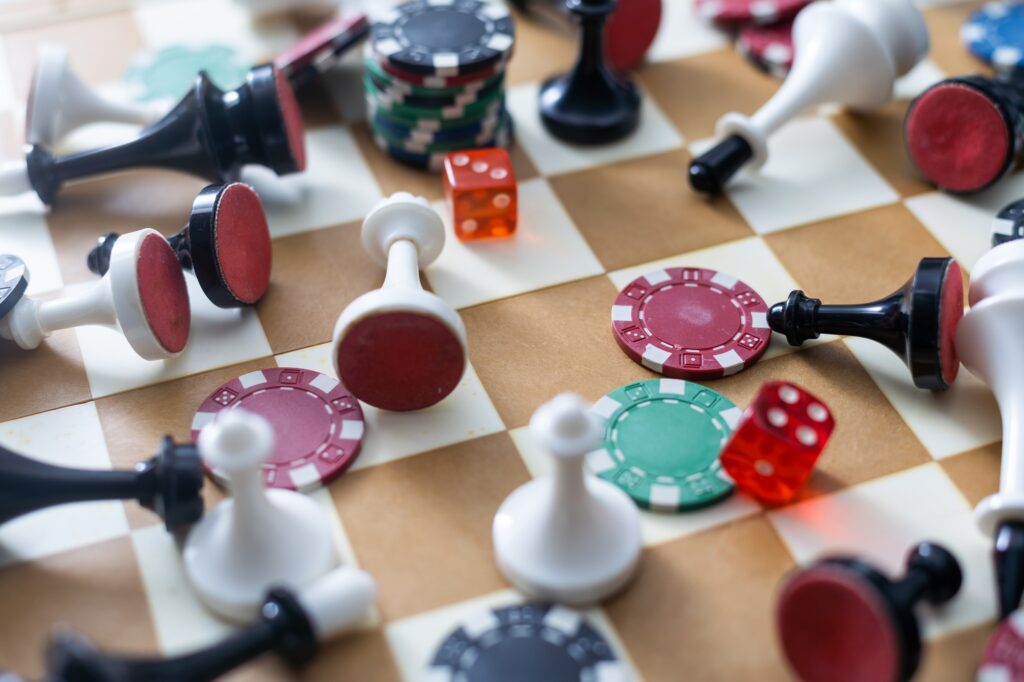 Wooden checkers, chess pieces, playing cards, board games on a light table close up.